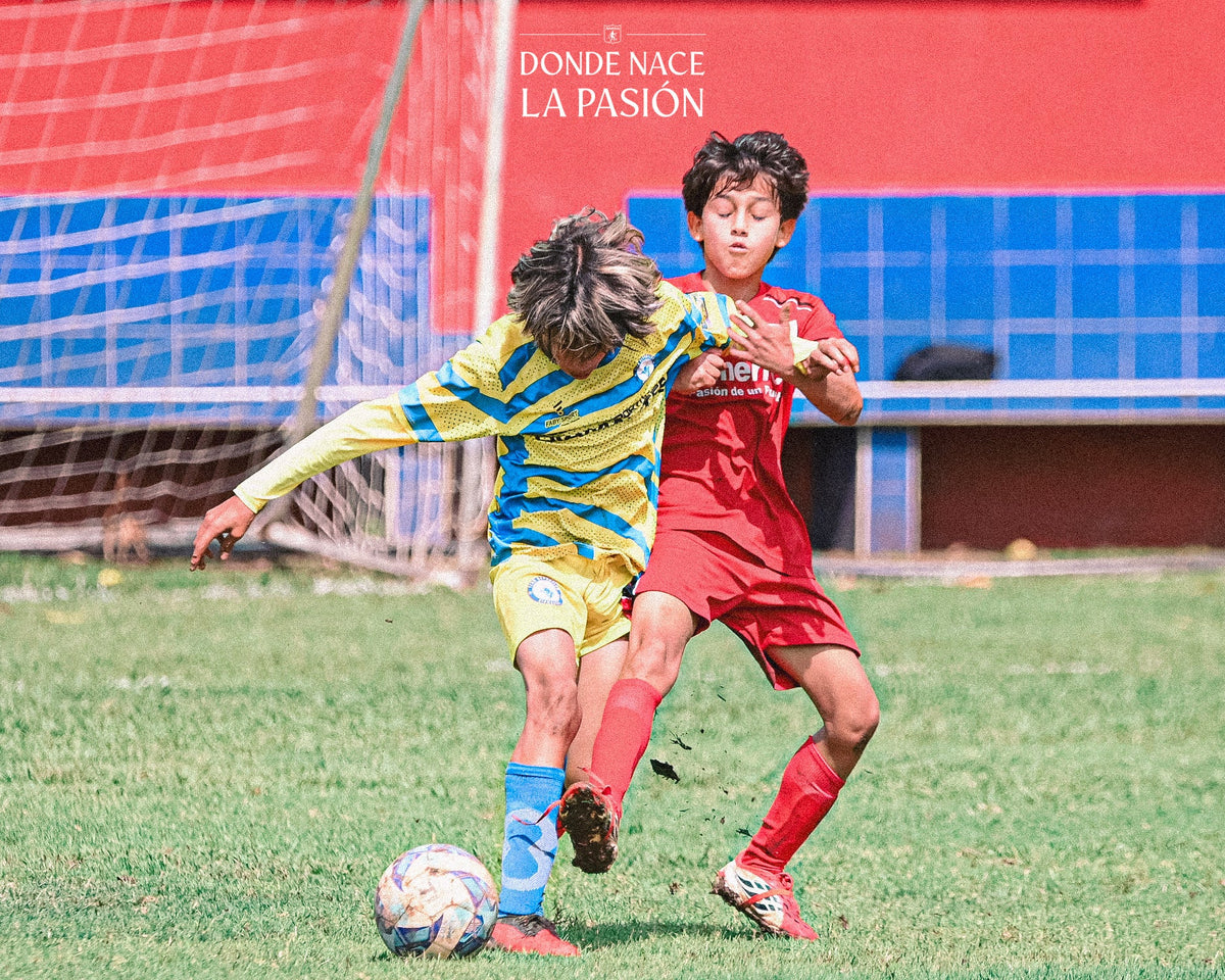 Dos niños disputan el balón en la jornada Sub-12 del Intercambio Deportivo de Academias América en la Sede Deportiva La Candela